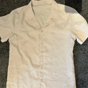 Kortärmad skjorta  - Lätt, stilren och otroligt bekväm – den här kortärmade skjortan är din nya favorit för varma dagar. Perfekt för både vardag och semester, med ett snyggt snitt som passar alla tillfällen. Skjortan har en klassisk krage och knäppning framtill. Passar lika bra på stranden som på after worken. Matcha med chinos, jeans eller shorts för en komplett look.