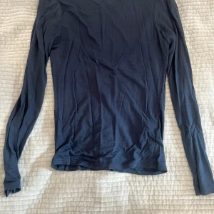 Svart långärmad topp med djup rygg - En mörkblå långärmad topp i mjuk bomull med enkel design och rundad, djup urringning i ryggen. Sitter tajt mot kroppen och har en klassisk passform. Storlek S. 📩 Skicka gärna ett meddelande vid frågor eller om du vill ha flera bilder! 🌸😊 📦 Jag skickar snabbt och packar alltid med omsorg!