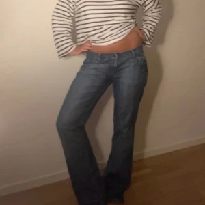 Blå bootcut jeans med låg midja - Säljer ett par blå jeans med bootcut-modell och låg midja. Jeansen har klassisk femficksdesign och är tillverkade i denim. Perfekta för dig som gillar en avslappnad men ändå snygg stil.