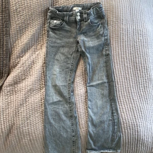 Grå jeans från Gina Tricot, stl 146 - Snygga grå jeans från Gina Tricot i storlek 146. Klassisk femficksmodell med bootcut och dubbla silverknappar i midjan. Jeansen har en cool tvättad look och är tillverkade i mjukt denimtyg. Perfekta för en avslappnad och trendig stil.