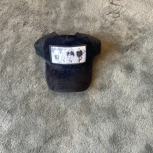 Svart keps från Emilio Pendenza - Svart keps från Emilio Pendenza med mesh på sidorna och en stor svartvit fotoprint framtill som ger en cool retrovibe. Kepsen har böjd skärm och justerbar passform. Perfekt accessoar för att lyfta din streetstyle.