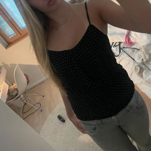 Svart prickig linnetopp  - Snygg svart linnetopp med små vita prickar och tunna axelband. Såå fin top och dont prickig mönster🥰 Storlek xs