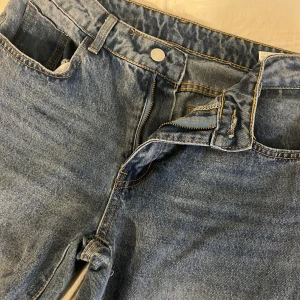 Blå raka jeans med klassisk look - Säljer ett par blå baggy jeans med raka ben. Jeansen är midwaist, dragkedja och knapp framtill samt snygga kontrastsömmar. Perfekta för en avslappnad och tidlös stil.