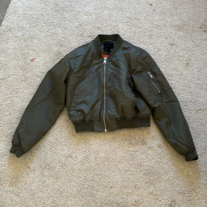 Olivgrön bomberjacka - Snygg olivgrön bomberjacka med orange insida 