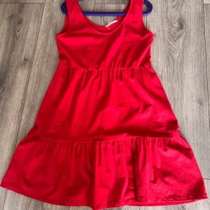 Röd ärmlös klänning från MNG - Säljer en snygg röd ärmlös klänning från MNG. Klänningen har en enkel design med en lätt rynkad midja och en volangdetalj vid fållen. Perfekt för en somrig look! 🌺 Storlek L