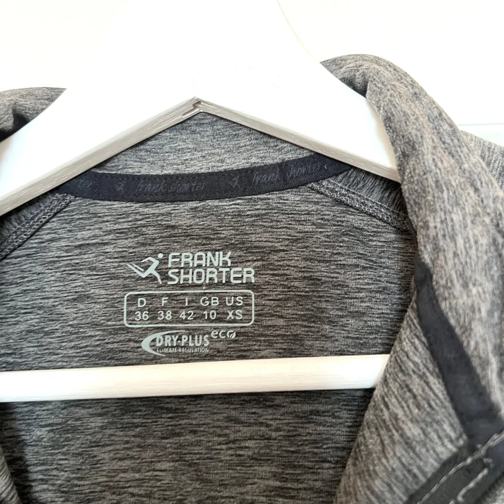 Säljer en grå långärmad tröja med halv dragkedja. Perfekt för träning med sitt DRY-PLUS material som håller dig torr och bekväm. Enkel och stilren design med logga på ärmen.. Sportswear.