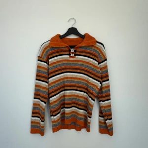 Randig ribbad tröja med dragkedja - Säljer en snygg randig tröja i orange, beige, svart och vit. Tröjan har en ribbad struktur och en unika spännen framtill. Perfekt för lite kyliga vår och sommarkvällar 🌸🌙🌒