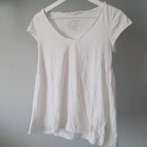 Vit v-ringad t-shirt från Odd Molly - Säljer en vit v-ringad t-shirt från Odd Molly med ett färgglatt tryck på ryggen. T-shirten är kortärmad, lätt utsvängd tack vare sprund på sidorna och gjord i bomull! 