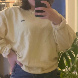 Gul sweatshirt från Lacoste - Säljer en gul sweatshirt från Lacoste med det klassiska krokodilmärket på bröstet. Tröjan har en avslappnad passform och långa ärmar med ribbade muddar. Perfekt för en casual look!