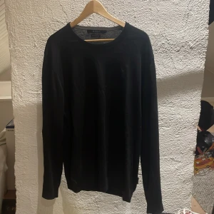 Svart tröja från Tiger of Sweden - Säljer en stilren svart tröja från Tiger of Sweden. Tröjan är tillverkad av fint italienskt garn och har långa ärmar. Perfekt för en elegant och minimalistisk look. Passar bra till både jeans och kostymbyxor.