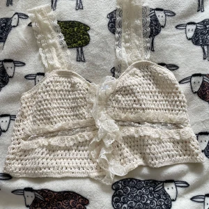 Vit virkad topp från Zara - Säljer en söt vit virkad topp från Zara med spetsdetaljer. Toppen har breda axelband och en fin volangkant nedtill. Perfekt för en somrig look! 🌼 endast använd en gång