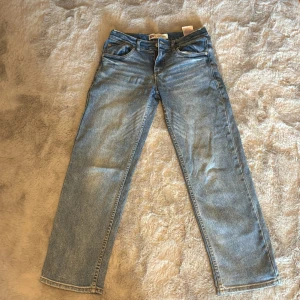 Blå jeans från Levi's - Säljer ett par klassiska blå jeans från Levi's med loose taper passform. De har en midwaist design och är tillverkade i jeansmaterial. Perfekta för en avslappnad stil.
