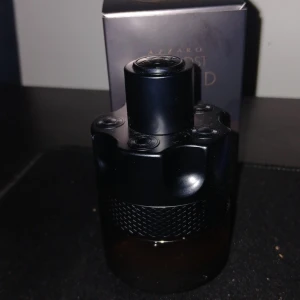 Azzaro The Most Wanted Parfym - Säljer en flaska Azzaro The Most Wanted parfym. Flaskan har en unik design med en mörk, stilren look och en texturerad yta. Parfymen kommer i en elegant förpackning som ger en lyxig känsla. Perfekt för den som vill ha en distinkt och minnesvärd doft.