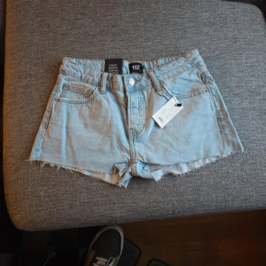 Ljusblå jeansshorts från 157 - Säljer ett par ljusblå jeansshorts från 157 i modellen Lexi. Shortsen har en klassisk femficksdesign och fransiga kanter för en avslappnad look. Perfekta för varma sommardagar! 🌞