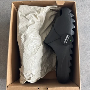 Svarta Adidas Yeezy Slide - Säljer ett par svarta Adidas Yeezy Slide i modellen Onyx. Oanvända i original box. Riktigt sköna tofflor till sommaren. Kan även byta tofflorna mot ett par nya i storlek 46 eller 47.