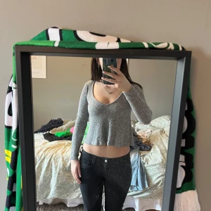 Grå ribbad croppad tröja - Säljer en grå ribbad croppad tröja med v-ringning. Tröjan har långa ärmar och är perfekt för en avslappnad stil. Passar bra till jeans eller kjol. Hör av dig vid intresse!