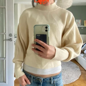 Beige stickad tröja från Zara - Säljer en stilren beige stickad tröja från Zara. Tröjan har en hög krage och långa ärmar, perfekt för kyligare dagar. Den är mjuk och bekväm, vilket gör den till ett mångsidigt plagg i garderoben. Passar bra till både jeans och kjol.
