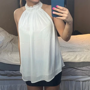 Vit ärmlös blus - Säljer en stilren vit blus med halterneck-design. Strl S/36. Säljes pga att den inte komemr till användning! 