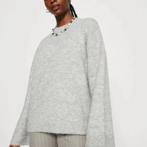 Grå stickad tröja - Mysig grå stickad tröja med lång ärm och avslappnad passform. Perfekt för kyliga dagar och enkel att matcha med olika outfits.