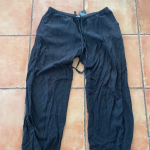 Svarta byxor från H&M Divided - Svarta linnebyxor från hm, uppsprättade längst ner men inget som syns. Storlek s