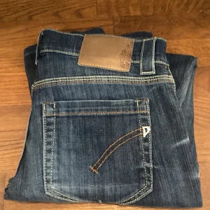 Blå jeans med brunt märke - Snygga blå jeans med ett brunt märke på baksidan. De har en klassisk femficksdesign och kontrastsömmar som ger en cool look. Perfekta för en avslappnad stil.
