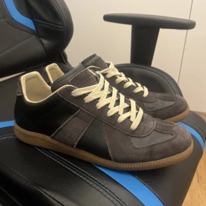 Grå och svarta sneakers med beige snörning - Snygga sneakers i grått och svart med beige snörning. Skorna har en klassisk design med rund tå och en bekväm gummisula. Perfekta för en avslappnad stil.
