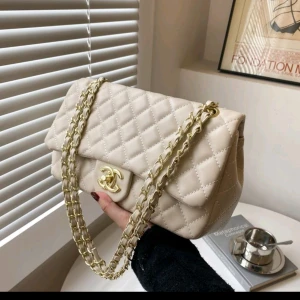 Beige quiltad axelväska - Elegant beige axelväska med quiltat mönster och guldfärgad kedja. Perfekt för att ge en lyxig touch till din outfit. Skriv pm for mer bilder 