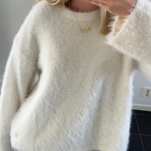 Fluffig vit stickad tröja - Supermjuk och fluffig vit stickad tröja med rund halsringning och långa ärmar. Perfekt för dig som gillar en cozy vibe och vill ha något riktigt gosigt till kyliga dagar.