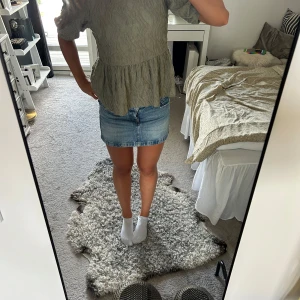 Grön blus från Gina Tricot - Supersöt ljusgrön blus från Gina Tricot i crinklat material. Blusen har puffiga korta ärmar, volang nertill och en snygg knytning i ryggen. Perfekt för dig som gillar en feminin och trendig look.