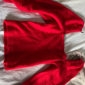 Röd stickad tröja från H&M - En riktigt snygg röd stickad tröja från H&M i storlek S. Tröjan har en klassisk rak passform med långa ärmar och ribbade muddar. Perfekt för dig som vill ha en färgklick i garderoben under kyliga dagar.
