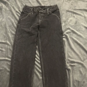 Svarta cargopants med kontrastsömmar - Säljer ett par svarta cargopants med vita kontrastsömmar och stora bakfickor. Byxorna har en klassisk cargoficka på sidan och raka ben. Perfekta för en chill och avslappnad stil.