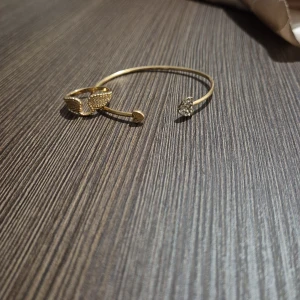 Guldfärgat armband och en ring - Snyggt guldfärgat armband med öppen design och en fin ring, Säljer båda för 100 kr men kan köpas separat OBS! står inte för frakt!