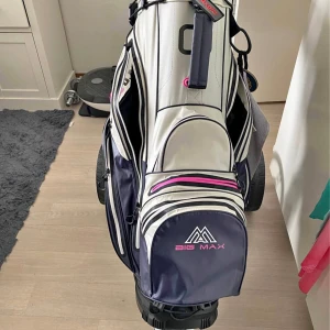 Vit och marinblå golfbag från Big Max höger dam - Snygg golfbag från Big Max i vit och marinblå med rosa detaljer. Väskan har flera fack, praktiska dragkedjor och tydliga fackindelningar upptill. Perfekt för att organisera golfklubbor och tillbehör. Stilig design med logga framtill och smarta förvaringsmöjligheter. Fraktar inte, vill gärna mötas upp. 