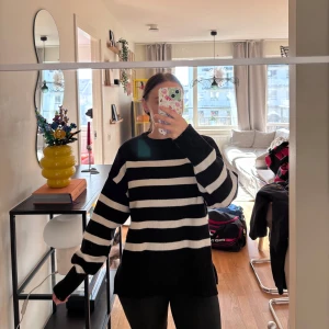 Svartvit randig stickad tröja - Säljer en oversized stickad tröja med breda svarta och vita ränder. Tröjan har lång ärm, rund halsringning och en loose fit som ger en chill vibe. Perfekt för lager-på-lager och funkar året runt när du vill vara både bekväm och snygg.