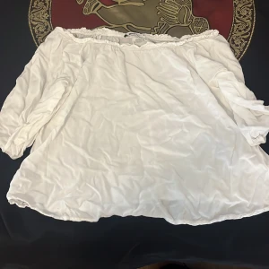 Vit offshoulder blus Gina Tricot - Säljer en vit offshoulder blus från Gina Tricot i storlek 34. Blusen har trekvartsärmar och resår upptill för en snygg passform över axlarna. Perfekt för dig som gillar en luftig och stilren look.