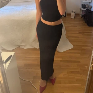 Svart ribbad långkjol från Stylein - Supersnygg svart långkjol från Stylein i modellen Perina. Kjolen är ribbad och har en tight passform som framhäver siluetten. Tillverkad i mjukt och stretchigt material med 80% rayon och 20% nylon. Orginal pris är 2400kr