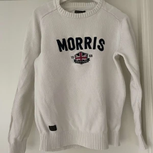 Vit stickad tröja från Morris - En Stilren Vit stickad tröja från Morris med broderad logga och brittisk flagga. Den har krymt lite i tvätten så den passar storleken S/M. Kan gå ner i pris vid snabb affär 