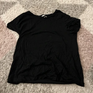 Svart basic t-shirt - En enkel svart t-shirt med rund hals och korta ärmar. Perfekt att matcha med jeans eller shorts för en clean och avslappnad look. T-shirten har en klassisk passform och är gjord i mjukt material.