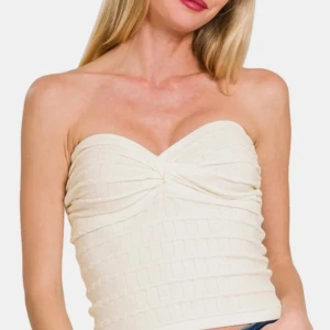 Krämvit bandeau tubtopp med twist - Snygg bandeau tubtopp i krämvitt med twistad detalj framtill. Toppen är ärmlös och har en lätt ribbad struktur som ger en cool look. Perfekt för varma dagar eller när du vill ha en stilren och enkel outfit.
