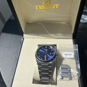 Tissot PRX blå urtavla stållänk - Snygg Tissot PRX med blå urtavla och stilren länk i rostfritt stål. Klockan har datumvisning och klassisk design med silverfärgade index och visare. Kommer i originalask och med extra länkbitar för perfekt passform.