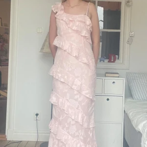 Ljusrosa långklänning 💕 - Supersöt ljusrosa långklänning från Boohoo med tunna axelband och flera volanger diagonalt över hela klänningen. Endast använd en gång. Perfekt för sommaren eller bal!💕