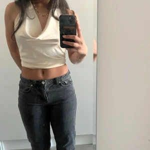 Vit croppad linnetopp med drapering - Säljer en vit croppad linnetopp med snygg draperad urringning och ärmlös design. Toppen har en stilren look och är perfekt för dig som gillar minimalistiska plagg med lite edge. Materialet är mjukt och lätt, vilket gör den superbekväm att bära.