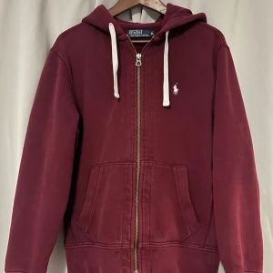 Vinröd hoodie från Polo Ralph Lauren - Riktigt snygg vinröd hoodie från Polo Ralph Lauren med vit broderad logga på bröstet. Riktig stilig att ha nu till sommaren😉