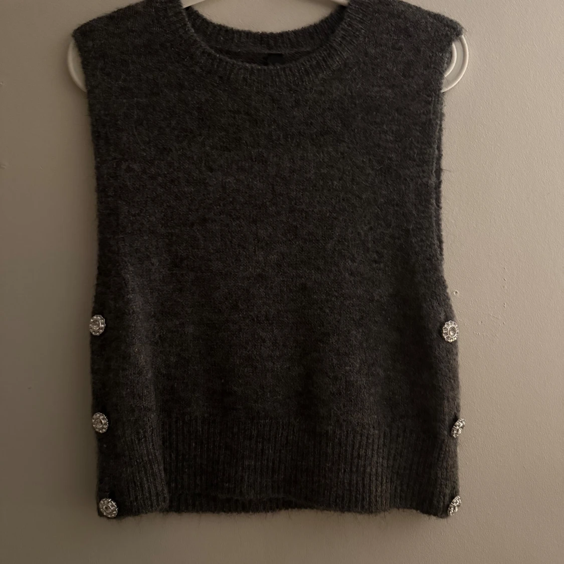 Mörkgrå stickad väst med glittriga knappar
