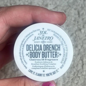 Sol de Janeiro Delicia Drench Body Butter 25ml - En mini burk med Delicia Drench Body Butter från Sol de Janeiro. Kommer i en lila rund plastburk med vitt lock. Innehåller en krämig, vit body butter med doften Cheirosa 59 och prebiotisk hibiskus samt Brazilian Soothing Complex. Oanvänd 