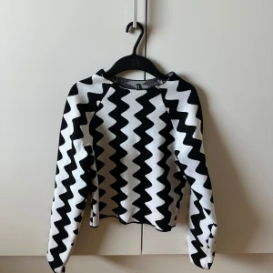 Svartvit zigzag stickad tröja ONLY - Cool stickad tröja från ONLY i storlek S med svartvitt zigzag-mönster. Tröjan har rund hals och långa ärmar, perfekt för dig som gillar grafiska prints och vill sticka ut lite extra. Skön och mjuk känsla, passar till jeans eller kjol.