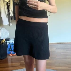 Svart stickad kjol från Zara - Svart stickad kortkjol från Zara med ribbad struktur och bred resår i midjan. Kjolen har en lätt utställd form. Storlek 152 men sitter som en XS. Säljer även en exakt likadan vit/ krämfärgad. Den har tyvärr aldrig kommit till användning.
