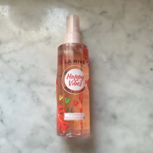 La Rive Happy Vibes Body & Hair Mist - Fräsch body & hair mist från La Rive i doften Happy Vibes. Flaskan är transparent med färgglada detaljer i rött, grönt och gult. Innehåller vitamin E och provitamin B5. Perfekt för dig som vill ha en lätt och fruktig doft till både kropp och hår. Endast lite använt som man ser på bilden