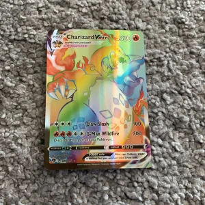 Charizard VMAX - Cool och sällsynt Charizard VMAX Pokémonkort med regnbågsglans! Perfekt för samlare och fans som vill ta sin kortlek till nästa nivå. Kortet har 330 HP och mäktiga attacker som Claw Slash och G-Max Wildfire. Ett måste för dig som älskar Pokémon!