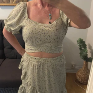 Blommigt set från Pieces - Supersött set med kort kjol och top från Pieces med små blommor i lila, rosa och grönt. Kjolen har volangkant nertill och resår i midjan för skön passform. Perfekt för sommarens alla tillfällen!